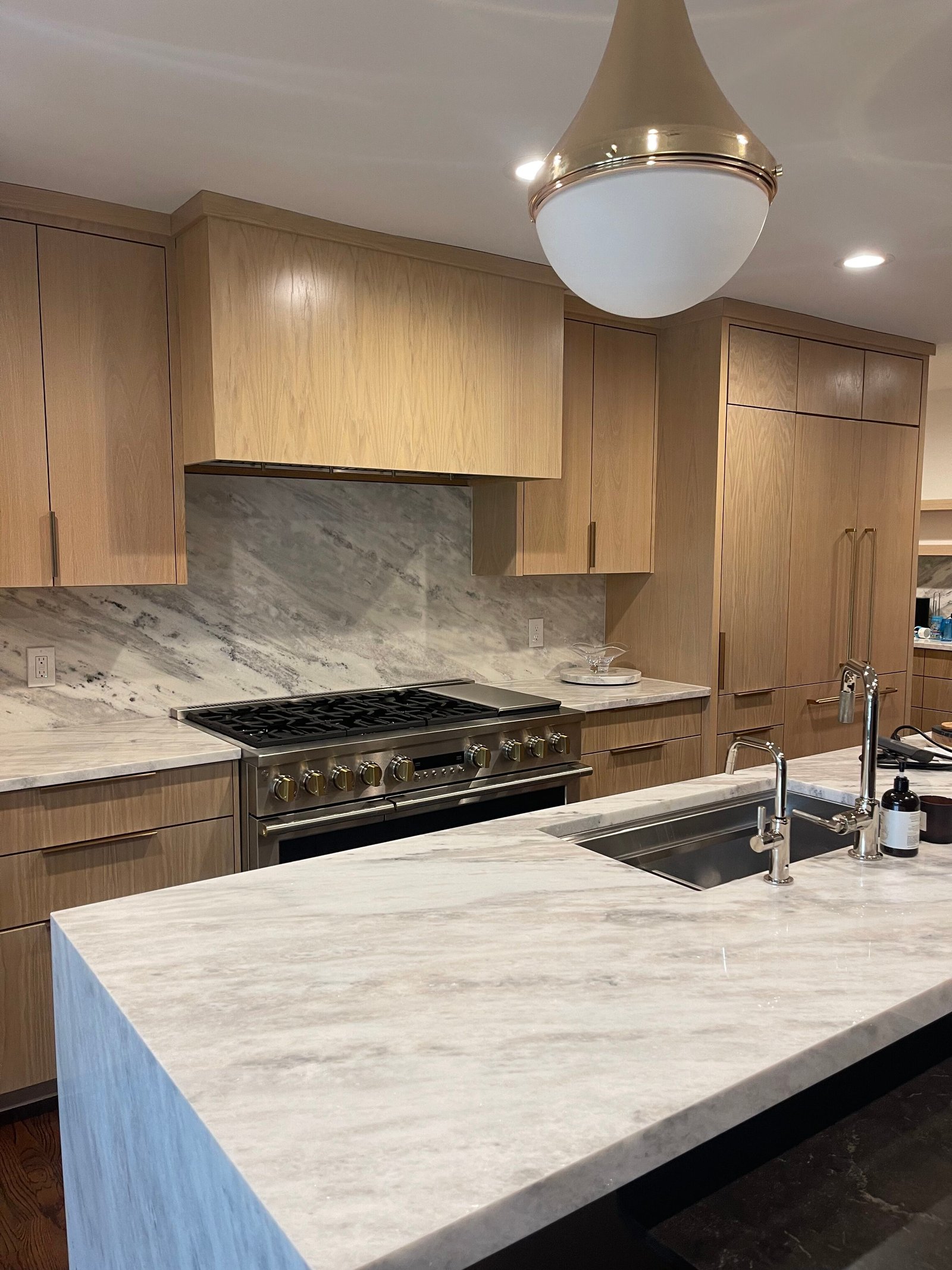 Natural wood flat-front kitchen with marble backsplash