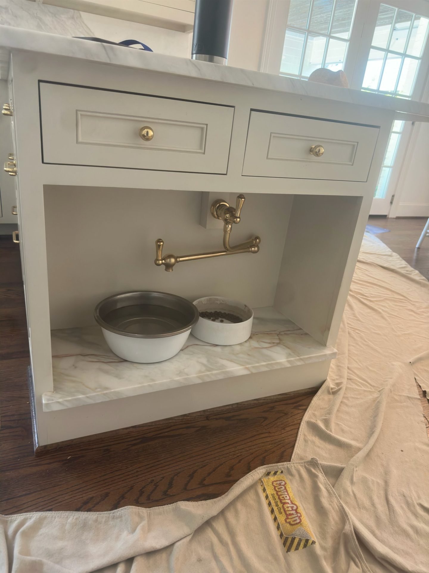 Custom built-in island pet feeding station with brass faucet and marble