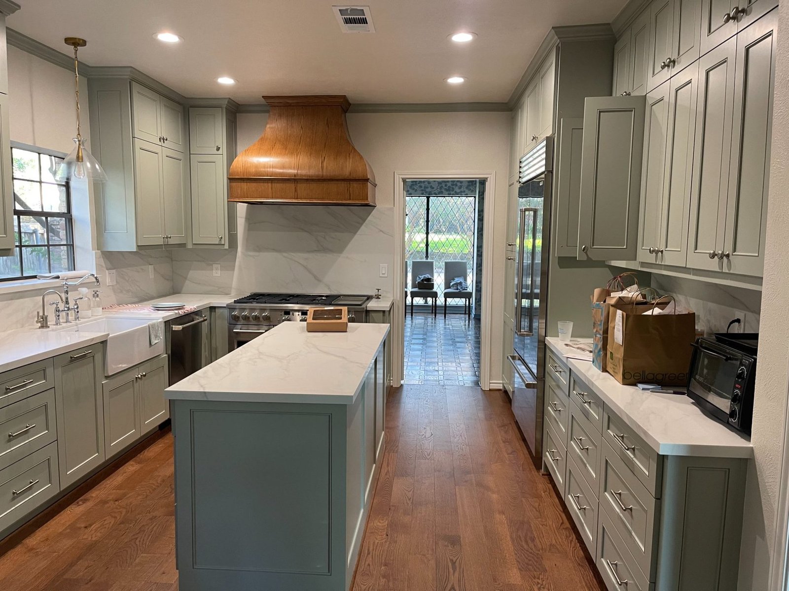 Sage green kitchen with custom wood range hood